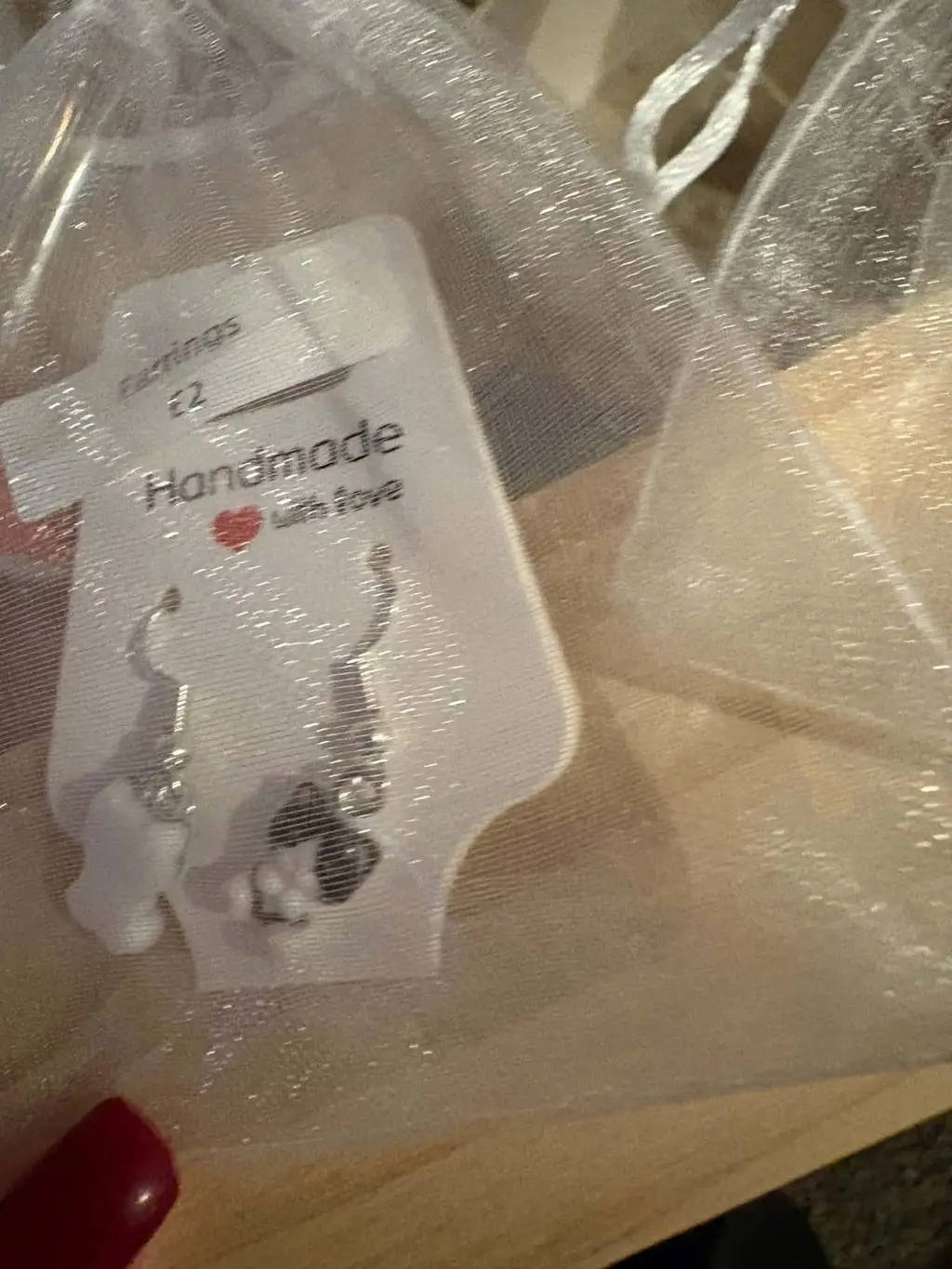 A pair of earrings with black and white kittens on a Handmade with love card, in an organza bag