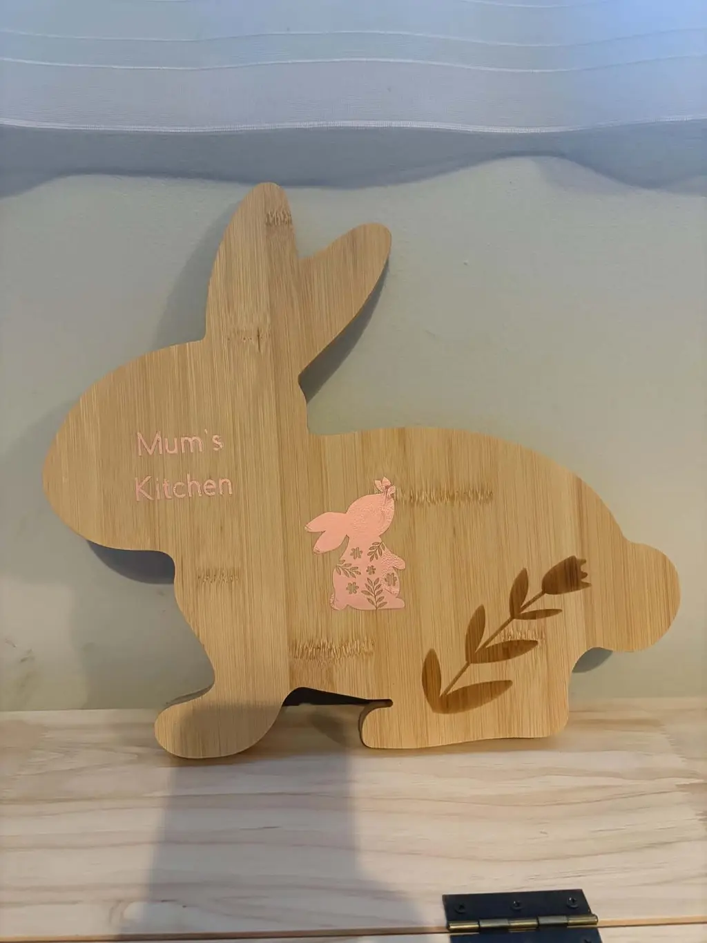 A bunny-shaped bamboo board with a flowery bunny, a flower sprig and the words Mum’s Kitchen