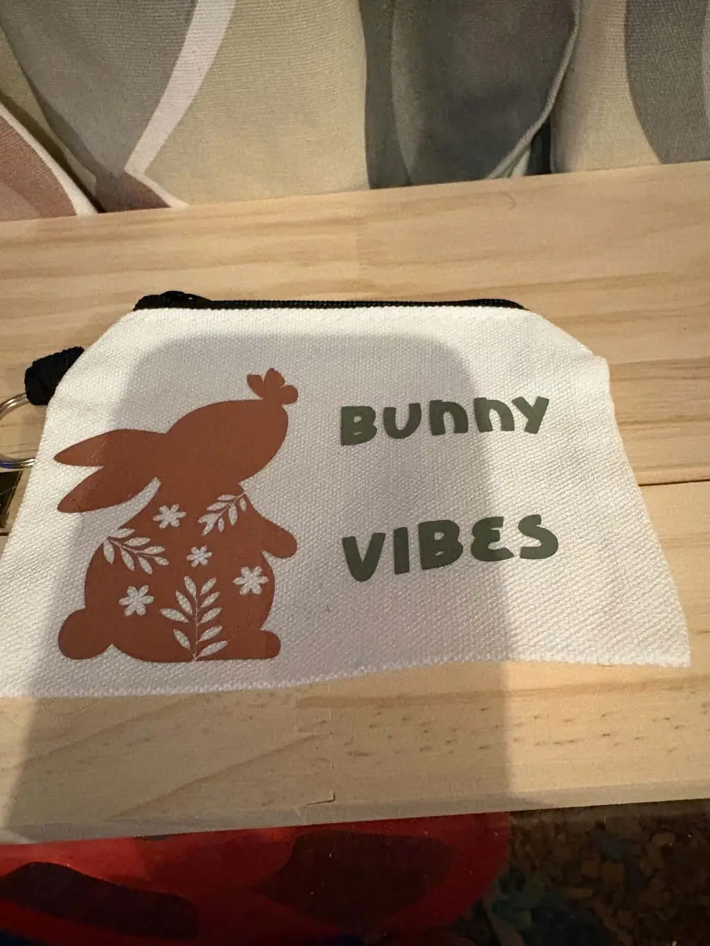 A white canvas zip purse printed with a brown flowery bunny and the words Bunny Vibes