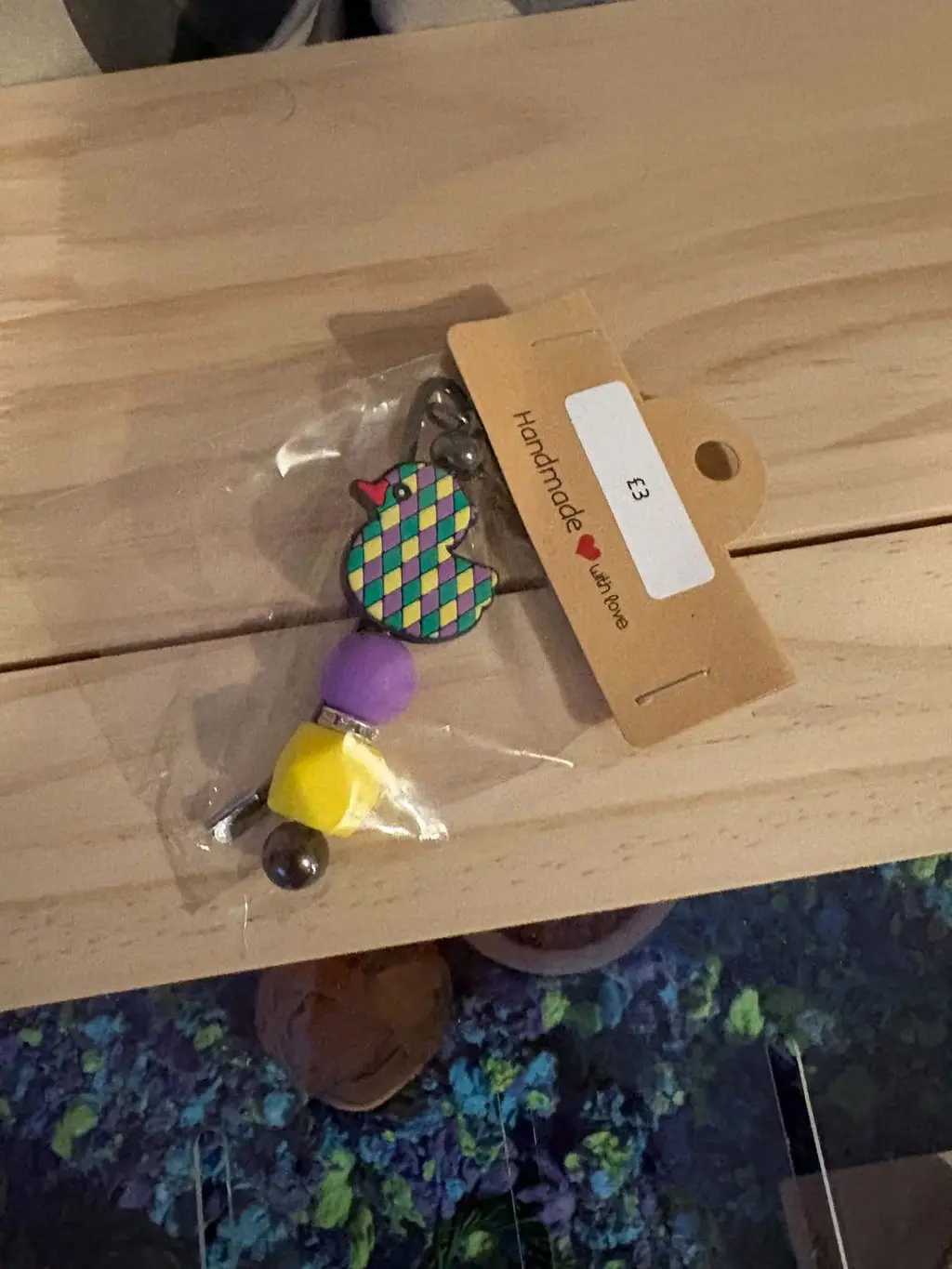 A bookmark with a green, purple and yellow duck charm on a Handmade with love card